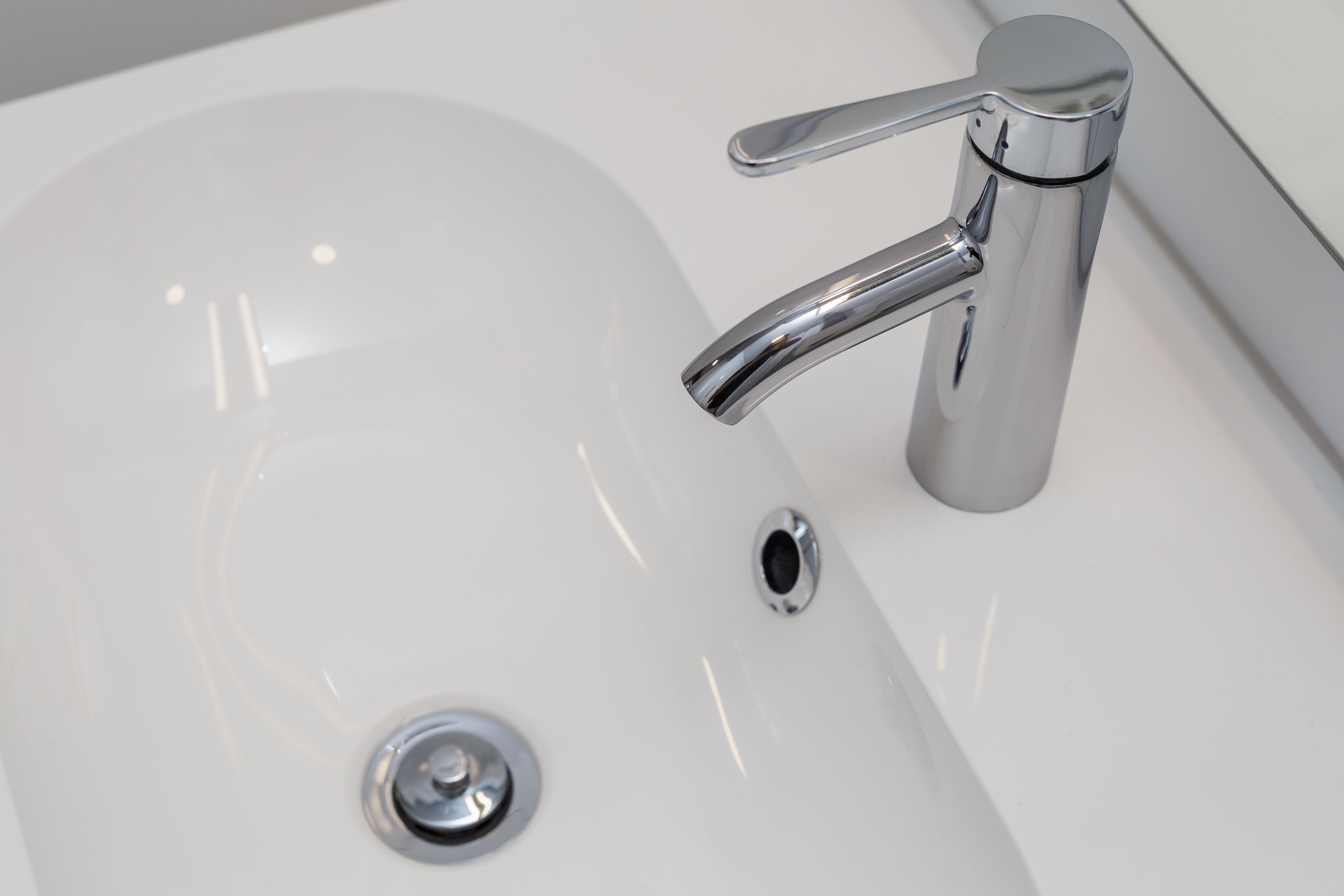 Un lavandino da bagno moderno con rubinetto cromato e uno scarico.