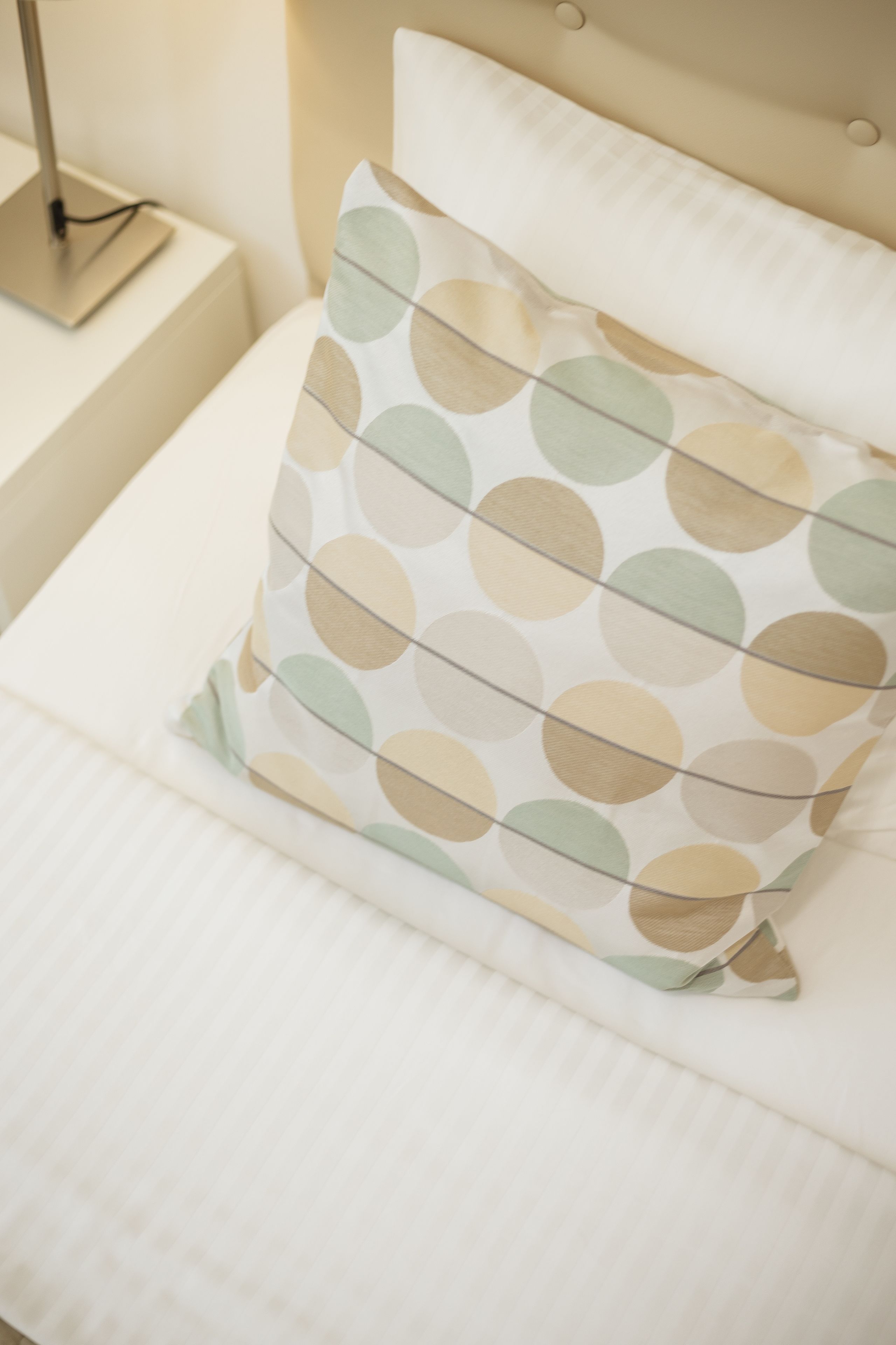 Un lit avec un oreiller orné d’un motif à pois.