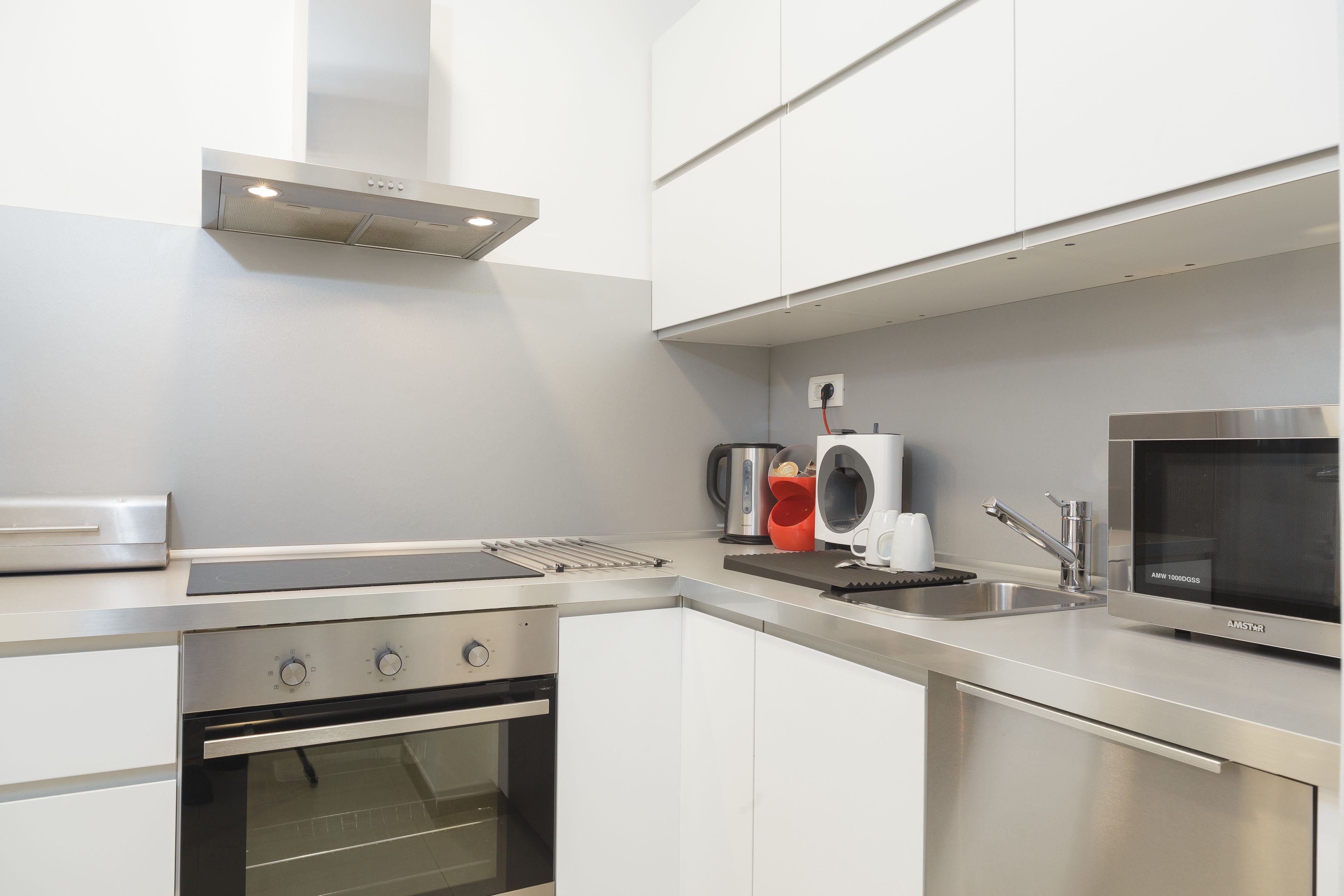 A modern kitchen with stainless steel appliances, white cabinetry, and a built-in oven.