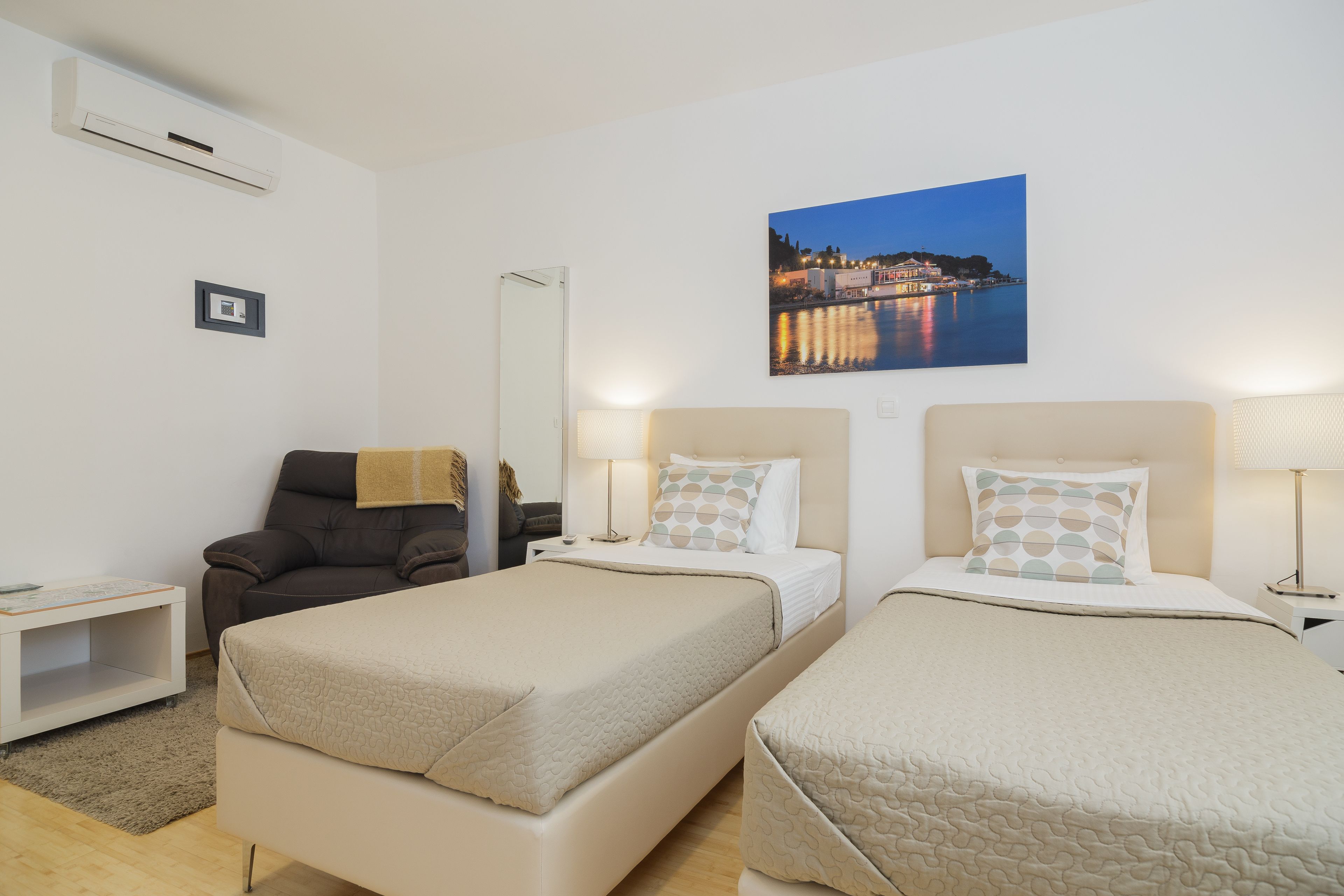 Camera d'albergo con due letti, un comodino, una sedia, una scrivania e un condizionatore d'aria a parete.