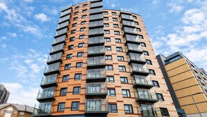Un immeuble résidentiel à plusieurs étages, doté d’un design moderne, de balcons et de grandes fenêtres.