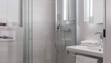 Ein modernes Badezimmer mit einer Duschkabine aus Glas, einem weißen Waschbecken und einer Toilette.