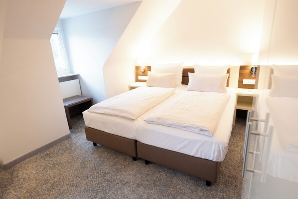 A modern hotel room with a large bed, a bedside table, and a nightstand. - Haus Delecke (Moehnesee)