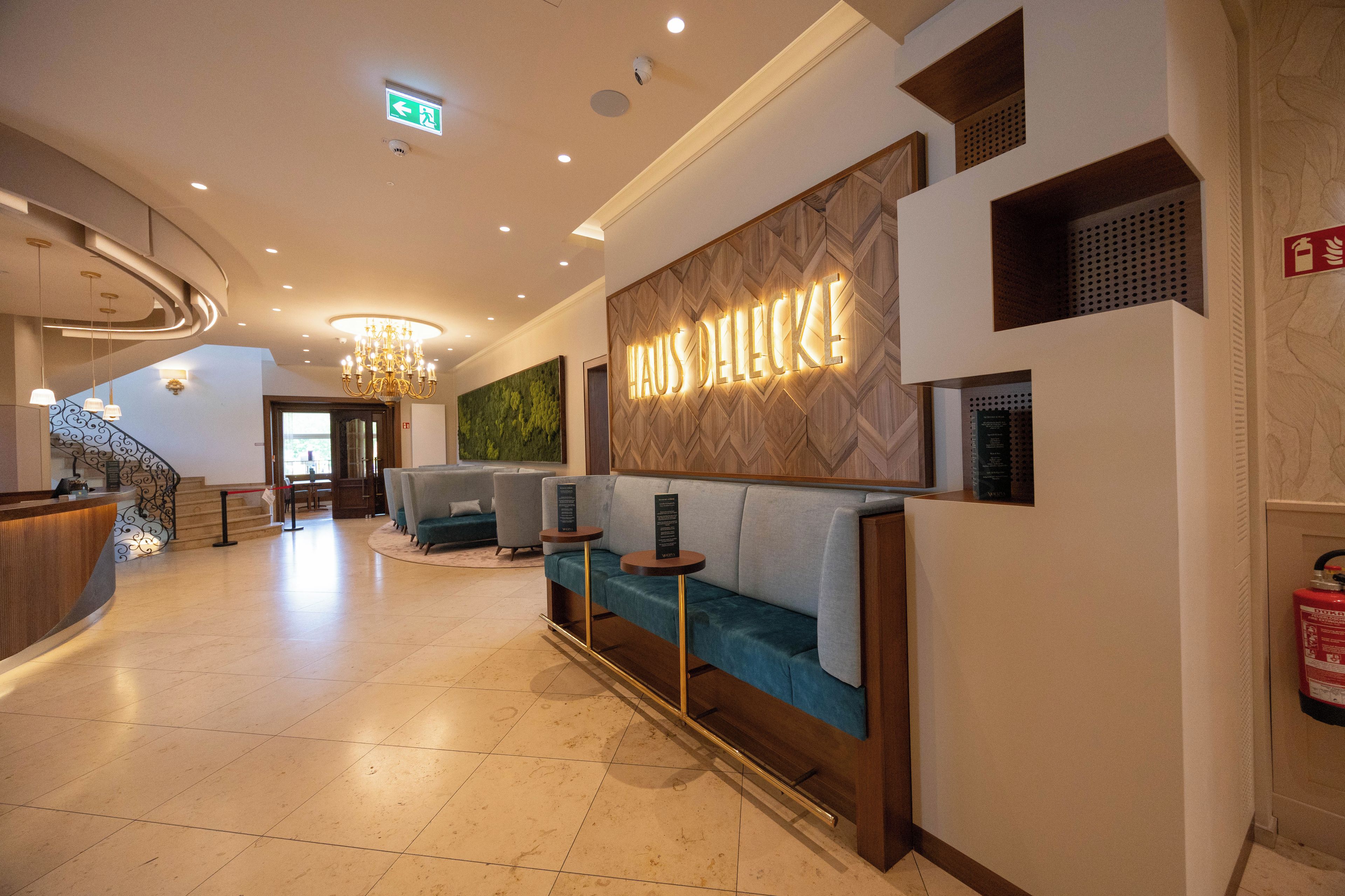 A hotel lobby with a reception desk, seating area, and a wall-mounted sign.