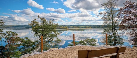 A bench overlooking a calm lake with a clear sky and distant hills.