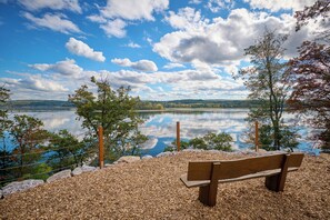 A bench overlooking a calm lake with a clear sky and distant hills. - Haus Delecke (Moehnesee)