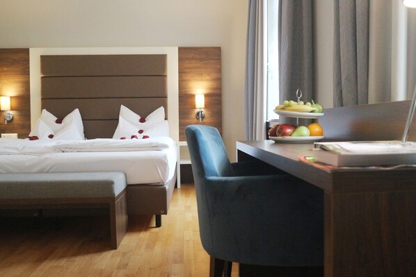 A hotel room with a bed, bedside tables, a desk with a laptop, and a fruit tray. - Haus Delecke (Moehnesee)