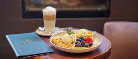 A dessert plate with ice cream, blueberries, and a strawberry on a wooden table.