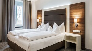 Una habitación de hotel con una cama grande, dos mesitas de noche y un tocador.