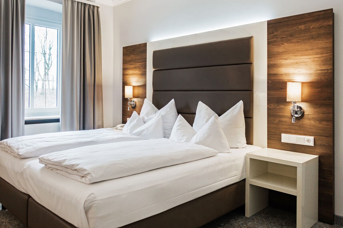 A hotel room with a large bed, two bedside tables, and a nightstand.