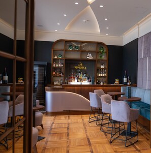 A bar area with a curved counter, seating, and a variety of bottles. - Haus Delecke (Moehnesee)