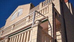 A multi-story building with a stone facade, a balcony with railings, and a visible window with shutters. - City Apartments Lani 4 (Dubrovnik)