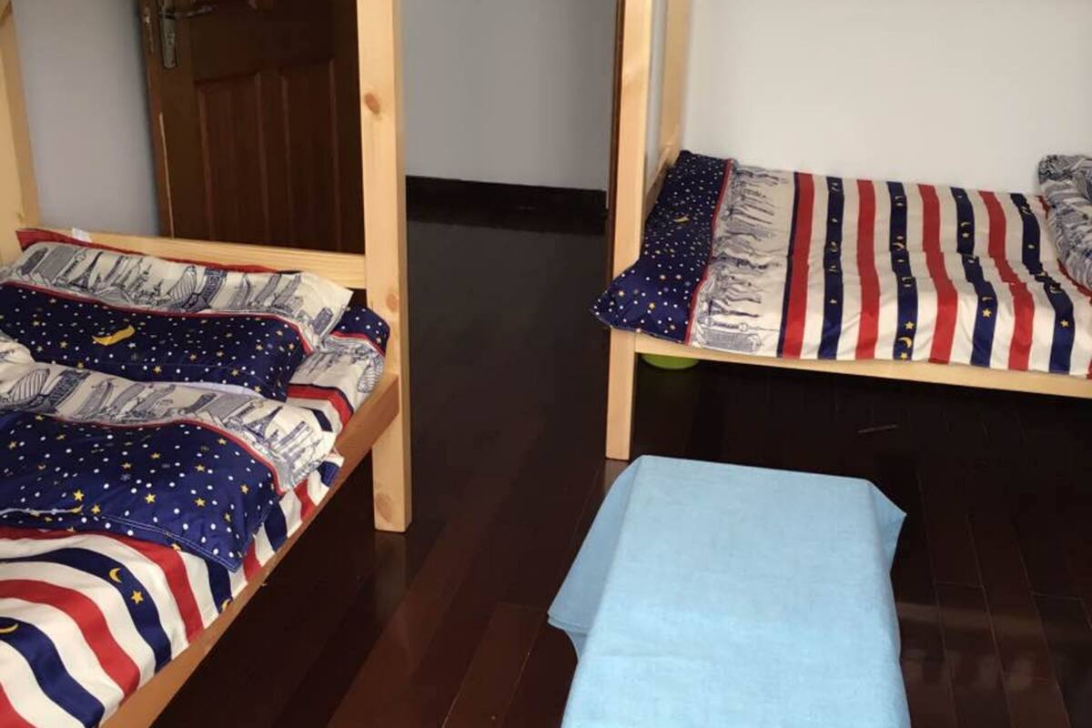 A room with two bunk beds, each with a bedspread featuring a star pattern. A bench is placed in the center of the room.