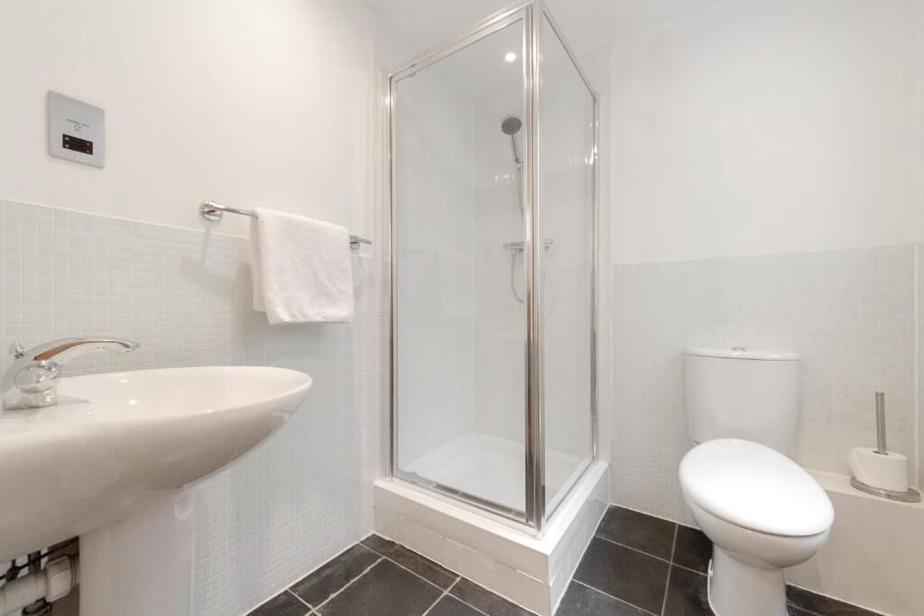 Une salle de bain avec une douche à parois de verre, un lavabo blanc et des toilettes.