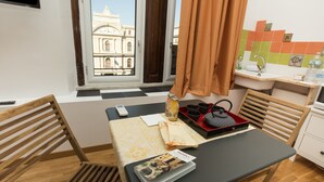 A room with a dining table, chairs, a window with a view of a historic building, a sink, and a tiled backsplash. - 5 Sirene (Naples)