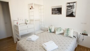 A bedroom with a bed, a white dresser, a mirror, and two framed pictures on the wall. - 5 Sirene (Naples)