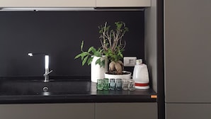 A modern kitchen with grey cabinets, a black countertop, a small potted plant, and a kettle. - 5 Sirene (Naples)