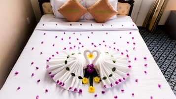 A neatly made bed with a heart-shaped towel arrangement and pillows labeled "Alena Hotel".