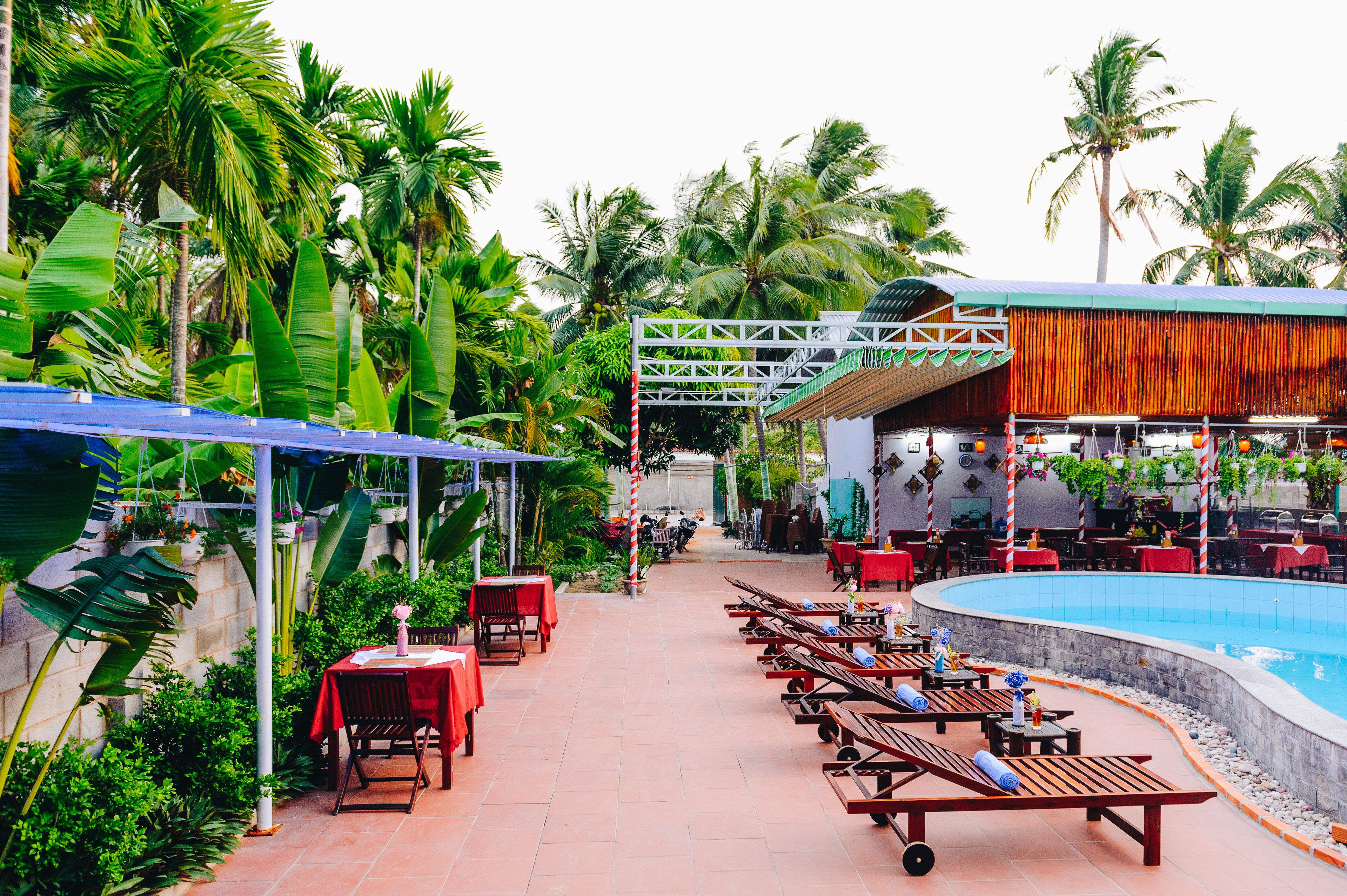 A poolside area with lounge chairs, tables, and a covered seating area.