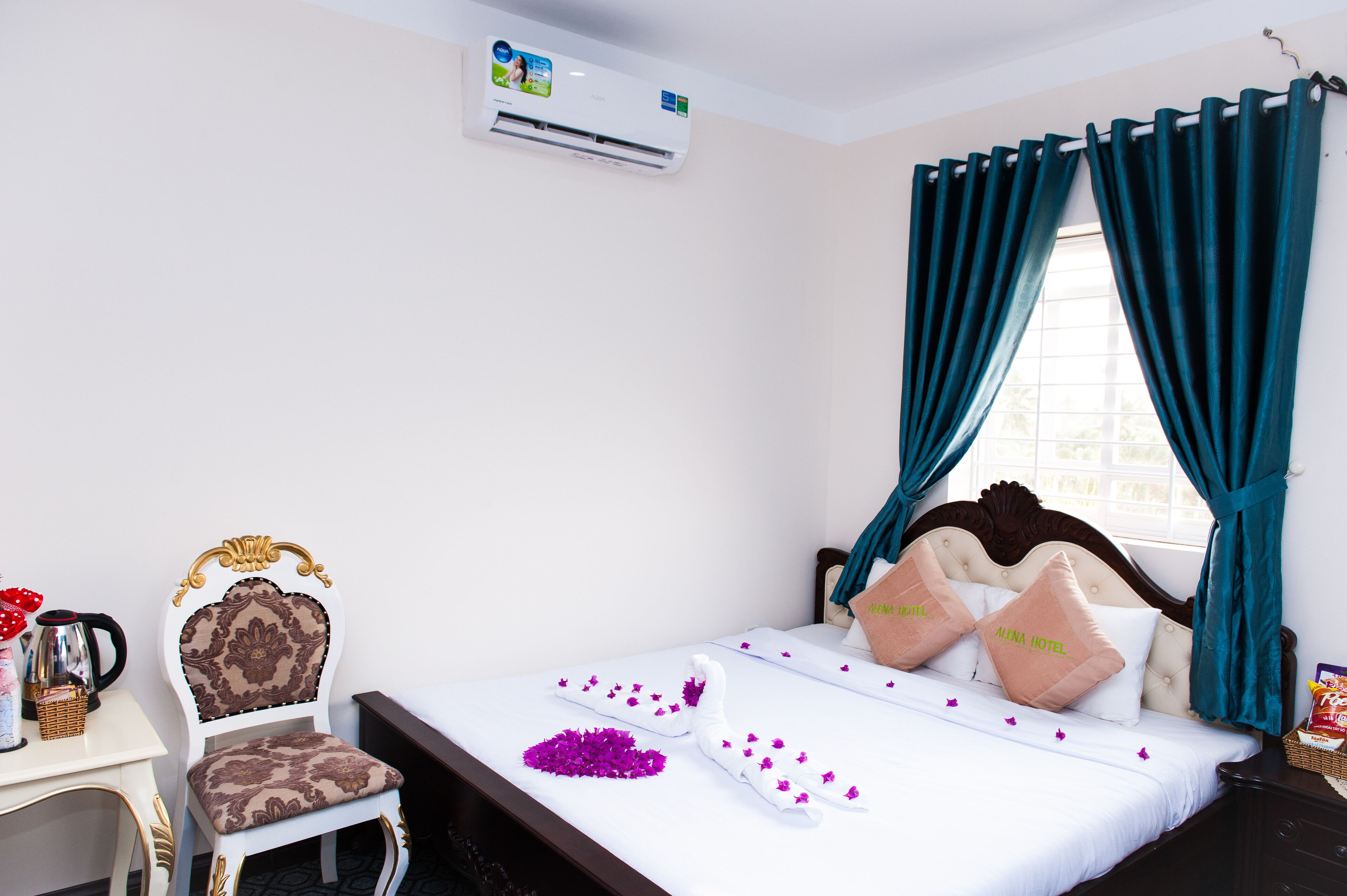 A hotel room with a bed, a chair, a desk, and an air conditioning unit.