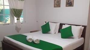 A neatly made bed with green and white bedding, two pillows, and two rolled towels. - The triple bbb villa (Negombo)