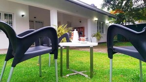 A patio with two black plastic chairs and a small white table with a teapot and cups. - The triple bbb villa (Negombo)