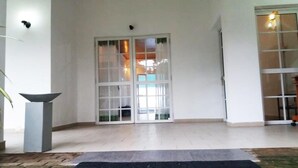 A room with a sliding glass door leading to a balcony, a small potted plant, and a light-colored tiled floor. - The triple bbb villa (Negombo)