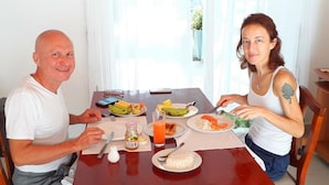 A dining table with plates of food, a glass of orange juice, and a bottle of juice. - The triple bbb villa (Negombo)