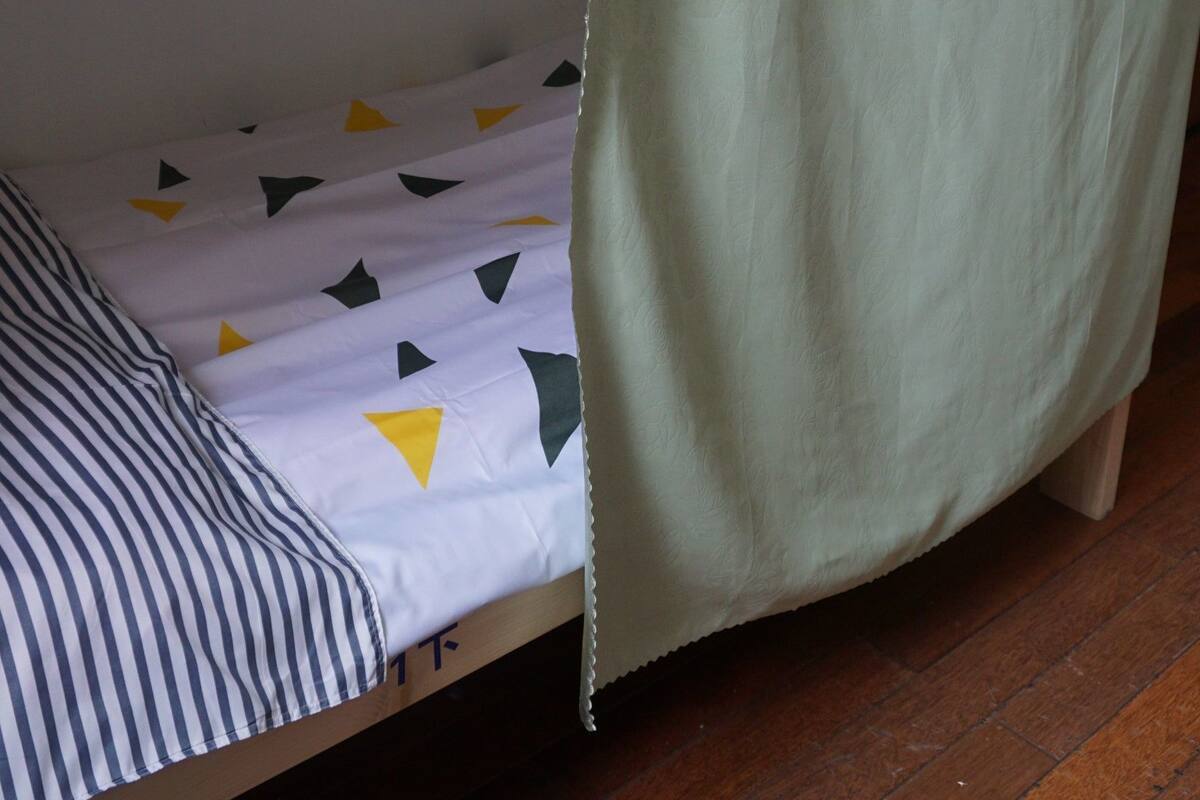 A bunk bed with a green curtain partially covering the lower bunk.