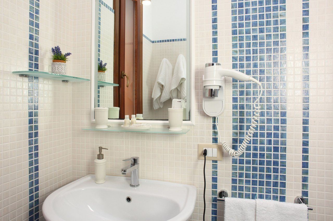 Un baño con lavamanos, espejo, toallero y secador de pelo.