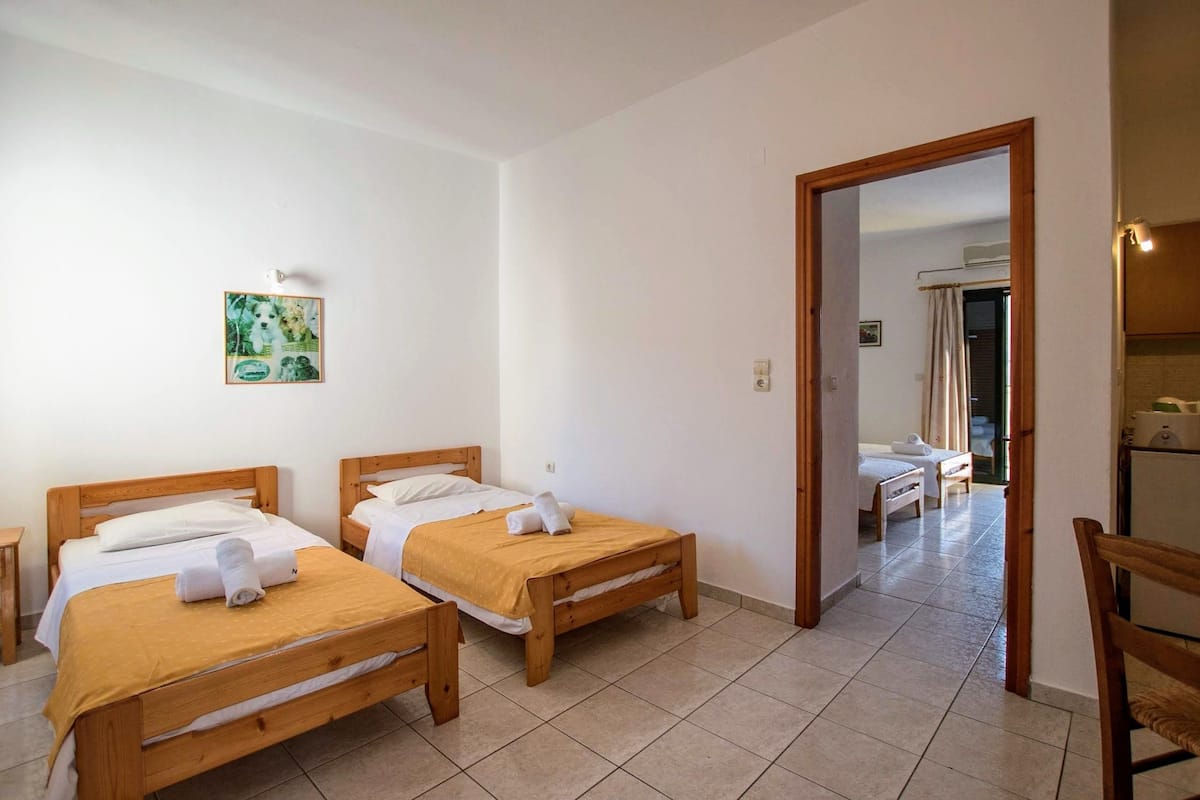 A room with two wooden beds, a small table, and a chair.