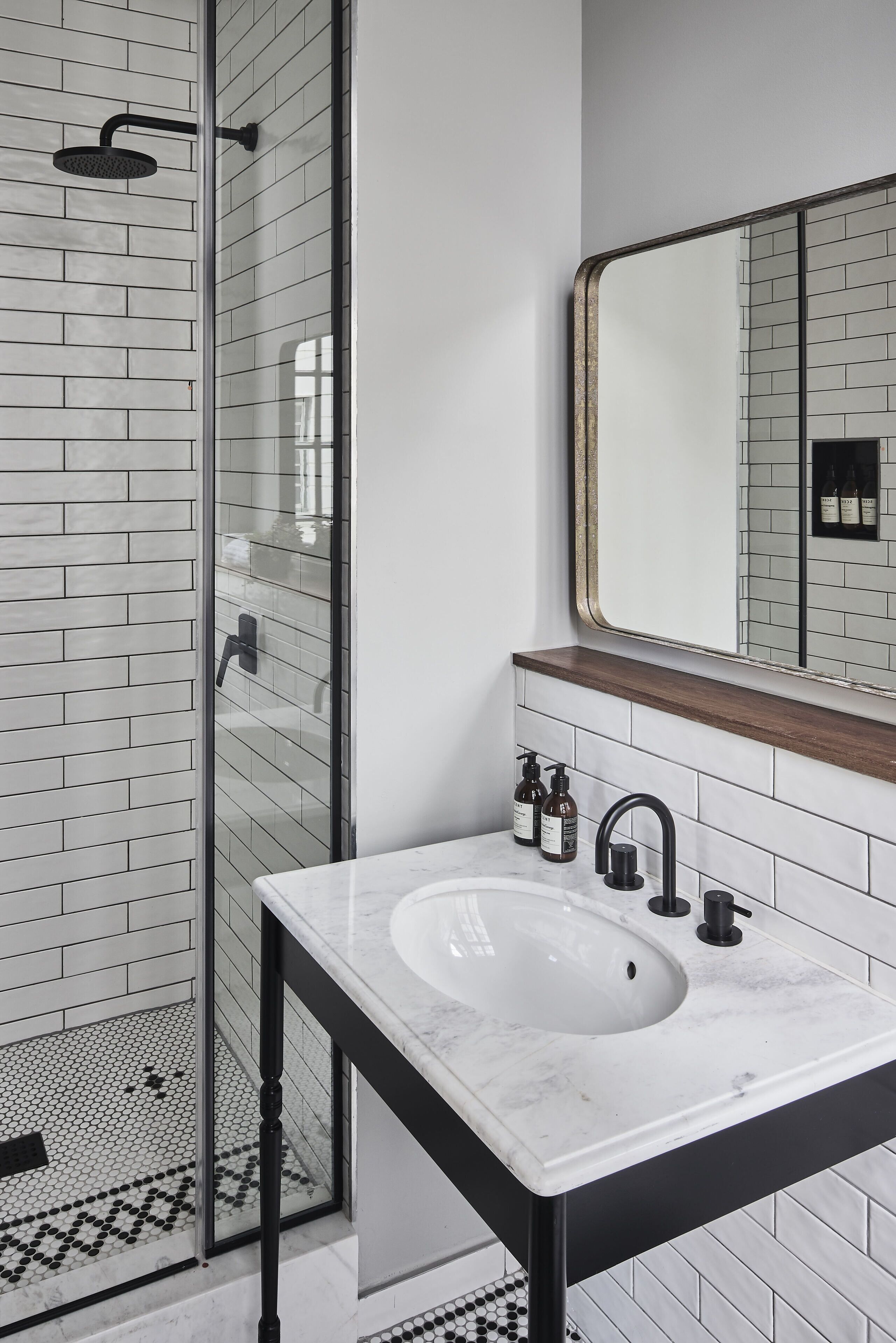 A bathroom with a glass shower enclosure, a white sink with a black faucet, and a mirror above the sink.