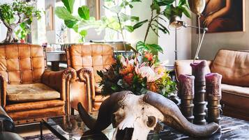A room with leather armchairs, a glass coffee table with a skull and horns centerpiece, and a large painting on the wall.