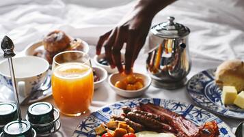 Mesa de café da manhã com ovos, bacon, tomates e suco de laranja.