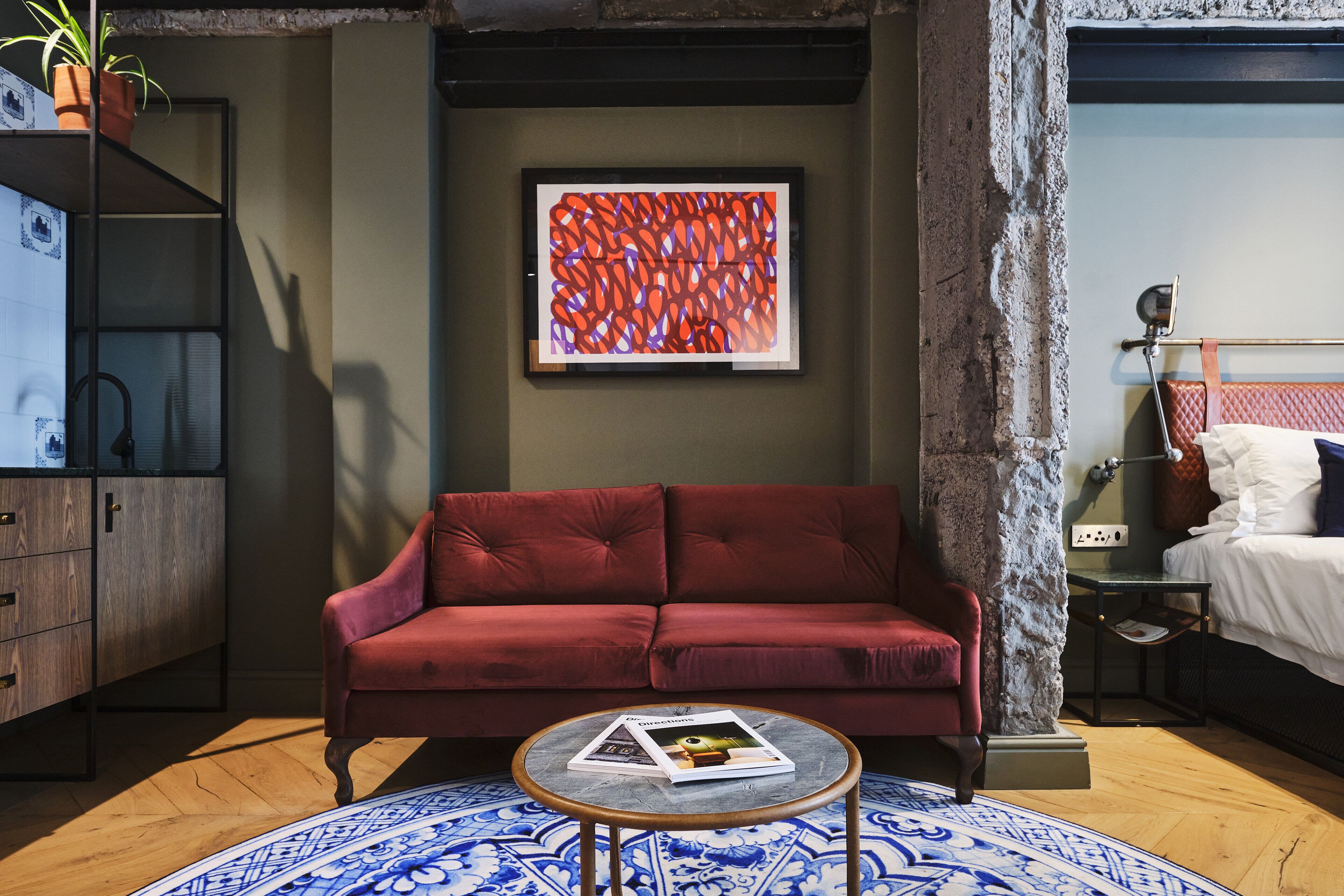 Un salón moderno con un sofá rojo, una mesa de centro redonda y un cuadro abstracto enmarcado en la pared.