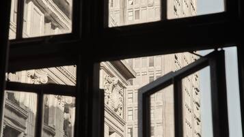 A view through a window of a building with classical architecture, featuring columns and detailed stonework.