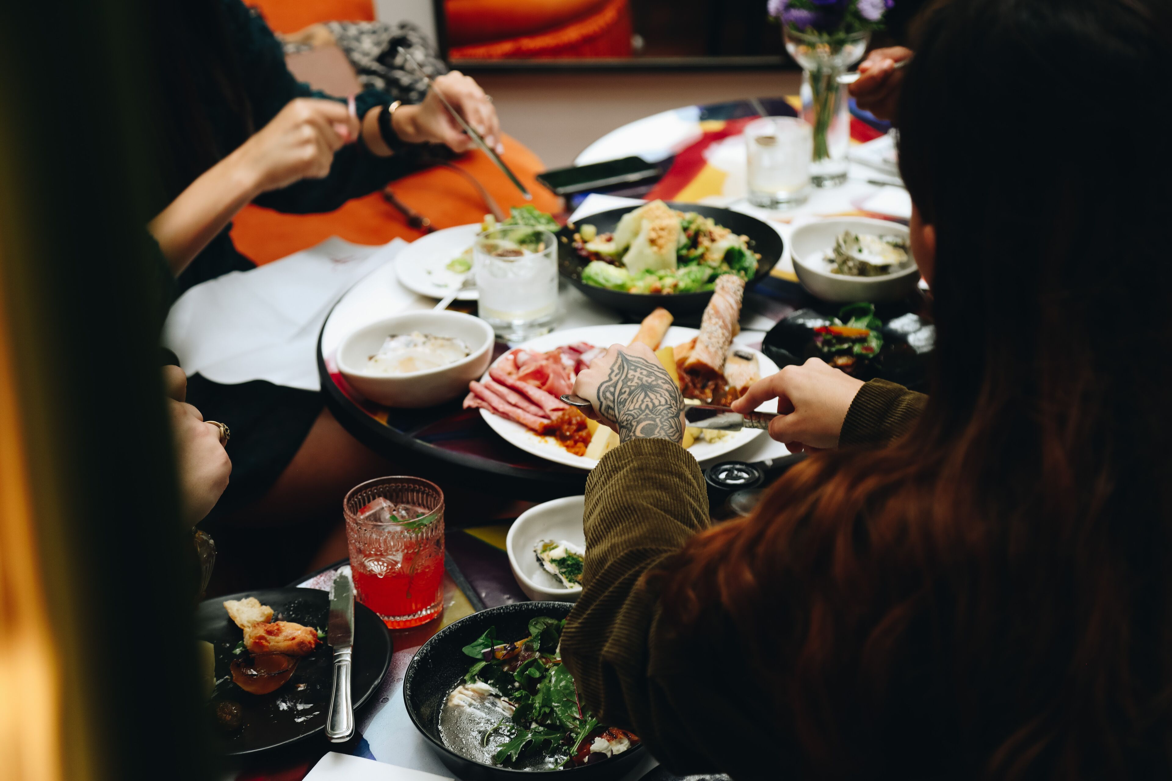 A group of people dining at a table with various dishes and drinks.