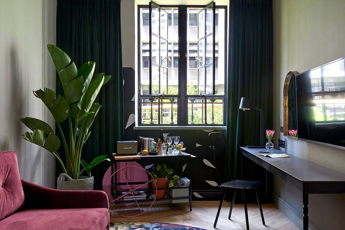 A room with a desk, chair, and a large potted plant.