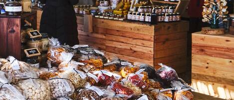 Un puesto de mercado con diversos productos envasados y un letrero que dice "The Honey Connoisseur Honey & Bee Products".