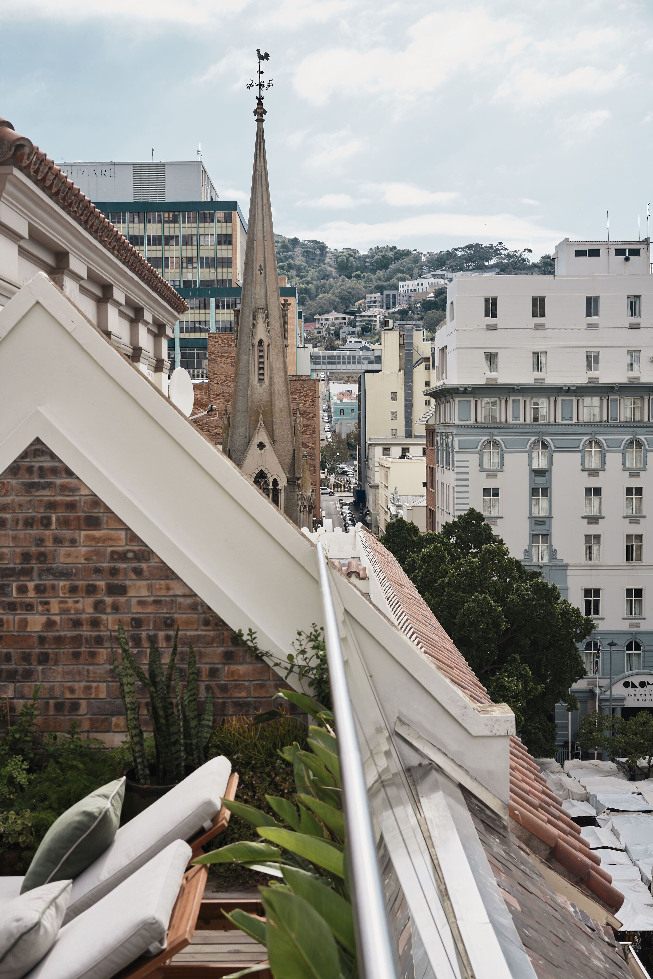 A view of a cityscape with a prominent church spire, a modern building, and a residential area with balconies.
