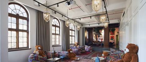 A spacious room with large windows, plush seating areas, and a chandelier.
