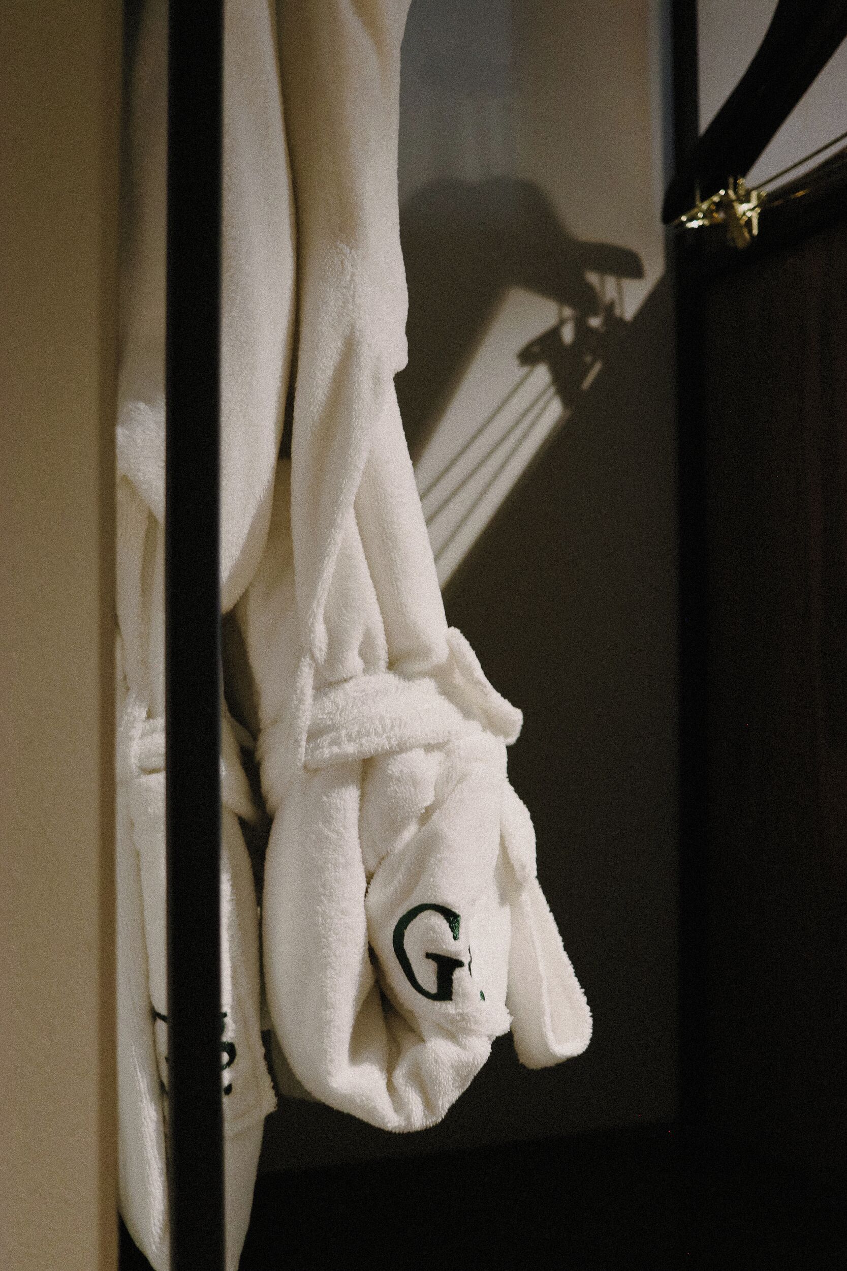 A white towel with a logo hanging on a dark door.