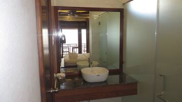 A bathroom with a large mirror, a white sink, and a shower area.