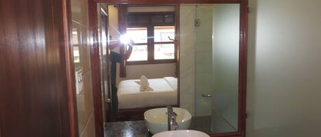 A bathroom with a large mirror, a sink, and a shower.