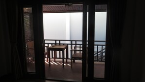 Un balcón con mesa y sillas, vista al cielo y barandilla de madera.