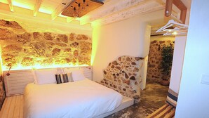 Un dormitorio con cabecera de piedra, estructura de cama de madera y un perchero.