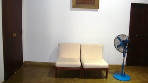 A room with two beige chairs, a blue standing fan, and a framed picture on the wall. - Mahawewa Nature Resort and SPA (Tangalle)