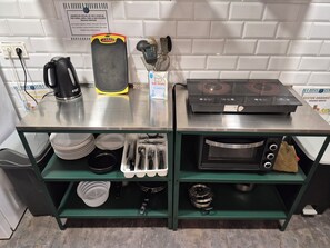 A kitchen area with a coffee maker, toaster, spatula, and a stove. - Balea Hostel (San Sebastián)