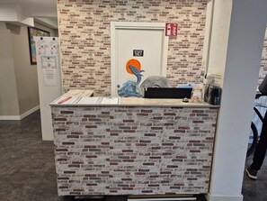 A reception desk with a brick-patterned backdrop, a 'STAFF ONLY' sign, and informational posters. - Balea Hostel (San Sebastián)