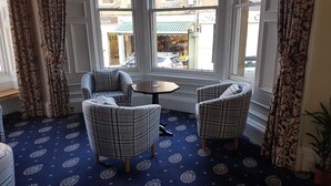 A room with two plaid armchairs, a small round table, and a patterned carpet. - George and Abbotsford Hotel (Melrose)